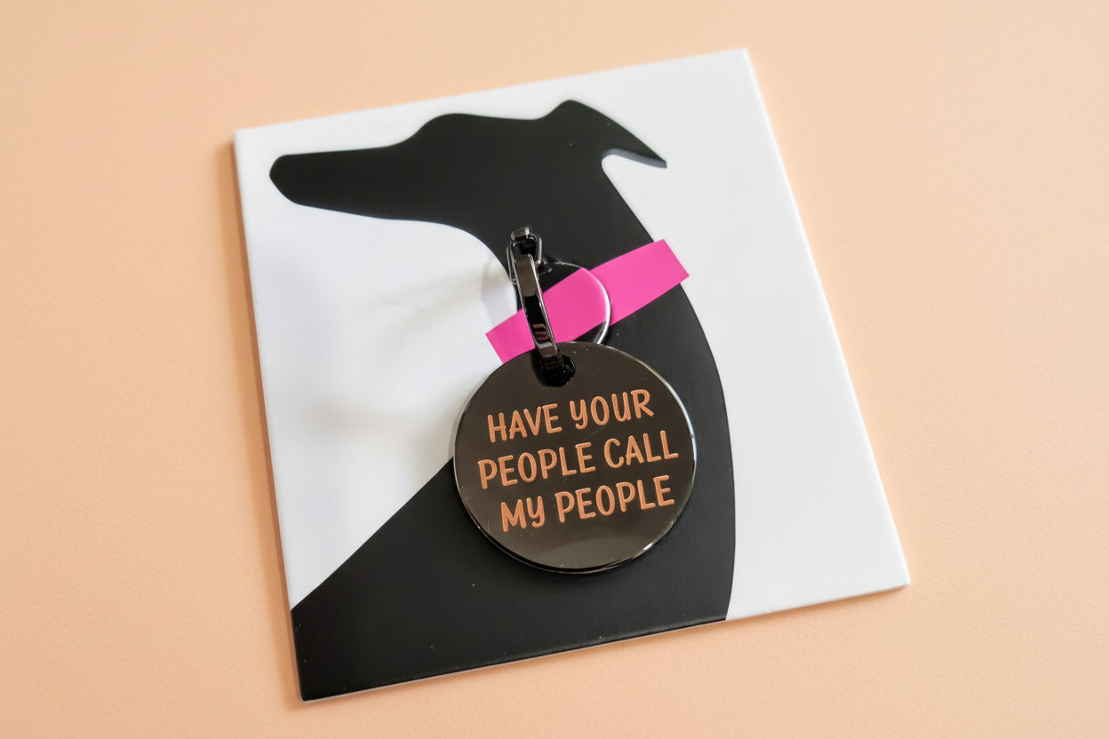 Dog tag with 'Have your people call my people' text on a black silhouette of a dog with a pink collar.